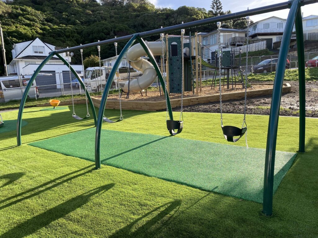 The new swing set with a mixture of synthetic grass and wetpour rubber surfacing.